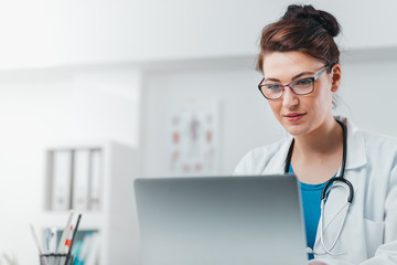 Wall Mural - Portrait of Young Woman Doctor working on laptop