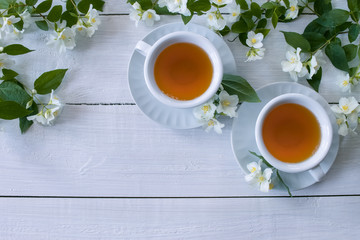 green tea in white cups and Jasmine flowers top view. Jasmine branches and two cups of tea on a white background. copy space. flat lay.