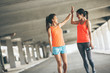 © BalanceFormCreative - Two young woman giving high five to each other.They relaxing after jogging on street.