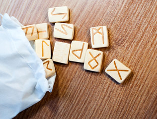 Wall Mural - Ancient wooden pine runes in a white bag on a wooden background. Magic. Divination. Future