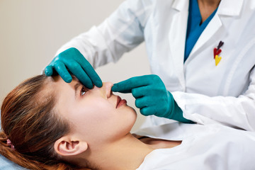 Lady with plaster on nose, doctor examining patients face after plastic surgery