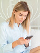 © woodpencil - Blonde beautiful woman with a smartphone chatting and sending photos in bed