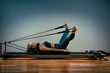 © Georgii - Young girl doing pilates exercises with a reformer bed. Beautiful slim fitness trainer on reformer gray background, low key, art light. Fitness concept