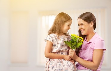 Wall Mural - Mother and daughter with bouquet of flowers on blurred background.