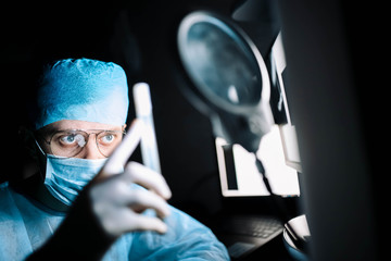 scientist doctor in a dark laboratory with a test tube of a medicinal product.
