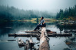 An Asian woman sitting down and looking up reflecting and pondering in the middle of foggy mountain at a lake