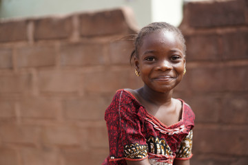 smiling african girl with a wet face after having taken a sip from the water borehole
