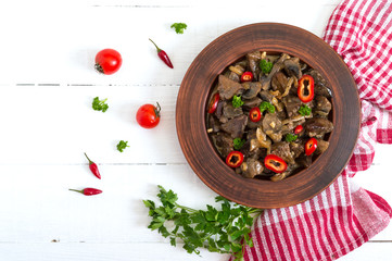 Wall Mural - Pieces of fried turkey liver with onions in a clay bowl on a white wooden background. Diet menu. Top view.