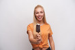 Indoor shot of young lovely cheerful long haired blonde lady with ice-cream on stick smiling happily at camera, being in nice mood while posing against white background
