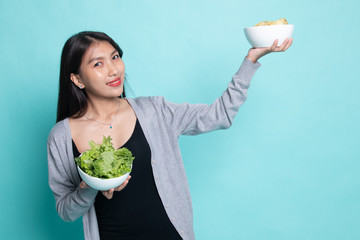 Young Asian woman with potato chips and salad.