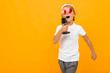 © Ivan Traimak - blond boy sings into a microphone on an orange background