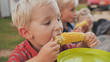 © Довидович Михаил - Young children eat boiled corn on village.