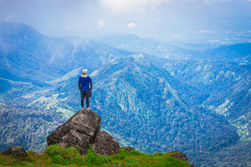 Beautiful landscape panorama of young Asian man enjoying looking at the stunning scenery on the high mountain before sunset.