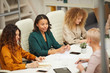 © Seventyfour - Group of businesswomen having meeting in modern office horizontal high angle shot