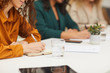 © Seventyfour - Horizontal shot of three unrecognizable young women sitting together at office table making notes during business meeting