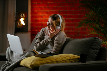 Wall Mural - Young woman in living room listening music. Beautiful woman with headphones.