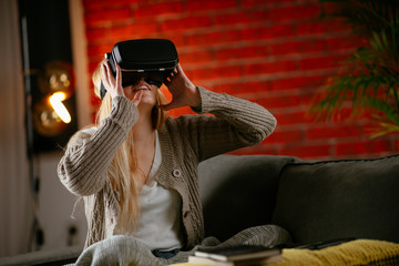 Wall Mural - Young woman using vr. Beautiful woman using virtual reality on sofa. .