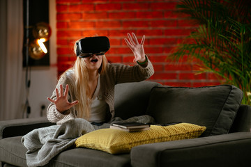 Wall Mural - Young woman using vr. Beautiful woman using virtual reality on sofa. .