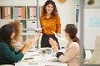 © Seventyfour - Attractive young adult woman with curly hair finishing presentation, her freiendly colleagues clapping hands