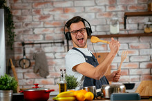 Young Attractive Man Singing In Kitchen. Handsome Man In Kitchen Having Fun.