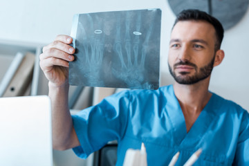 Wall Mural - selective focus of handsome orthopedist looking at x-ray