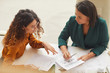 © Seventyfour - Two young businesswomen working on new business plan sitting together at office desk, high angle horizontal shot
