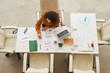 © Seventyfour - Young businesswoman with curly hair working alone in modern office horizontal from above shot