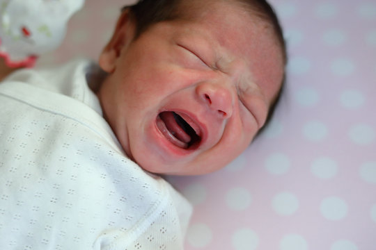 cute newborn baby cry on bed