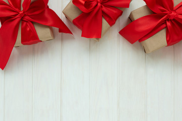 Wall Mural - Gift boxes wrapped brown craft paper and red ribbon on white wooden background. Valentines day or Mothers day celebration concept. Top view