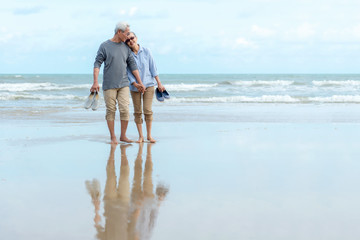 Lifestyle asian senior couple happy walking hug and relax on the beach.  Tourism elderly family travel leisure and activity after retirement in vacations and summer.