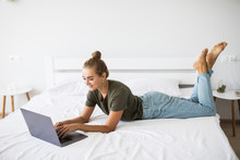 Portrait Of A Relaxed Young Woman Using Laptop In Bed At Home