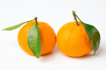 Fresh, bright fruits. Two tangerines with a leaf on a white isolated background.