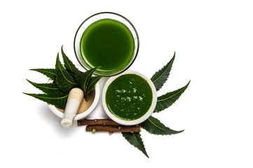 Wall Mural - Medicinal Neem leaves in mortar and pestle with neem paste, juice and twigs on white background