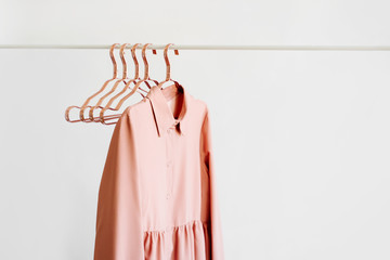 Wall Mural - Pale pink dress with metallic hangers on white background. Elegant fashion outfit. Spring wardrobe. Minimal concept.