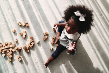 Wall Mural - african american girl child playing letter block on floor