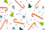 Fototapeta Uliczki - New Year background with Christmas candy cane, festive tree and balls. Pattern on white desk top-down