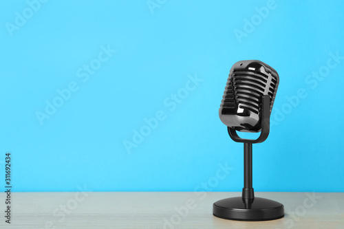 Fotomural Retro microphone on wooden table against light blue background, space for text