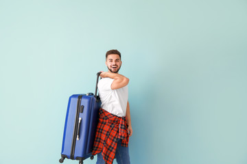 Sticker - Young male tourist with luggage on color background