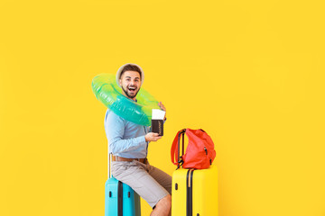 Canvas Print - Young male tourist with luggage on color background