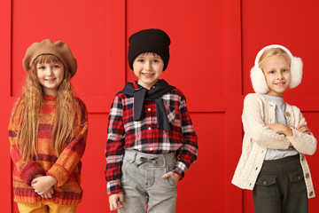 Wall Mural - Cute little children in autumn clothes near color wall