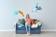 © Pixel-Shot - Excited woman with heap of clothes on sofa indoors