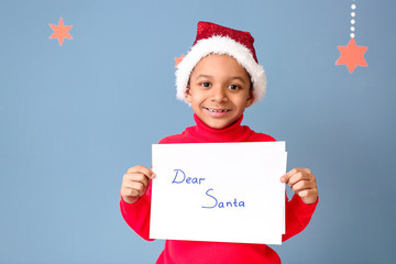 Wall Mural - Cute African-American boy with letter to Santa Claus on color background