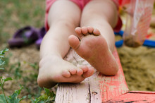 Child's Bare Feet Stained In Sand On A Sandbox