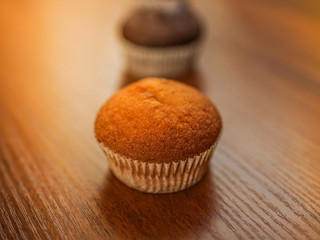 Sweet muffins on the brown wooden table.