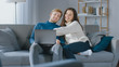 © Gorodenkoff - Cute Young Couple Use Laptop Computer, Have Fun, Laughs, while Sitting on the Couch in the Cozy Apartment. Couple Shopping on Internet, Using Social Media, Watching Videos and Streaming Content