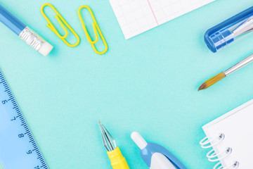 Stationery flat lay: notebooks, pens, pencils, paper clips, brush on a light turquoise background. Stationery in classic blue and yellow colors. Trend colors 2020. Copyspace.