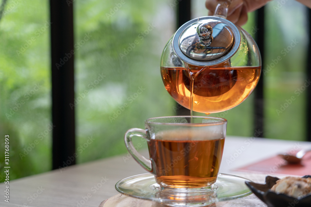 Tea set in clear glass jug and dessert. During leisure time drinking ...
