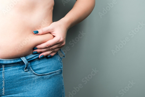 Fotografía A plump woman in jeans, a fold of skin in her hand