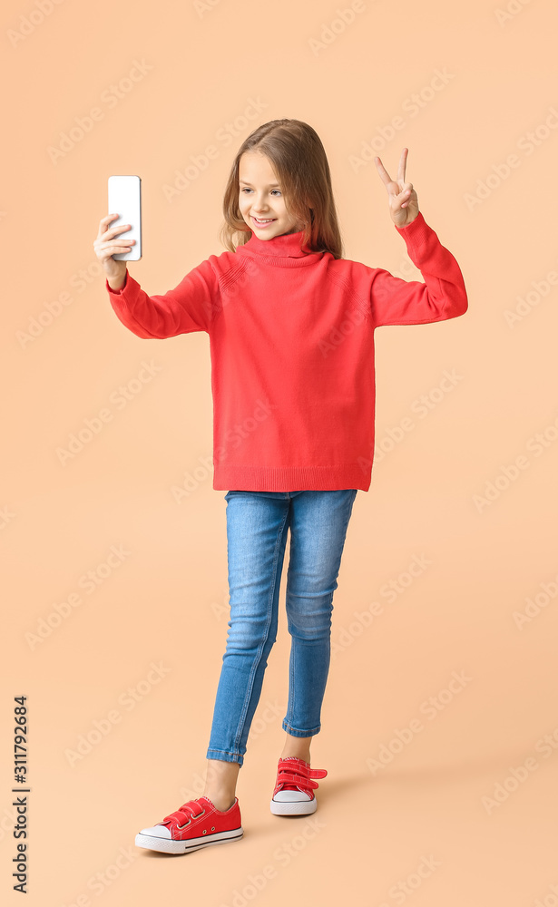 Cute little girl taking selfie on color background