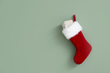 Christmas sock with gift hanging on color wall